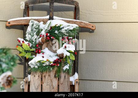 Weihnachtsdekorationen und Piniennadeln und rote Beeren bedeckt Schnee im Dezember Stockfoto