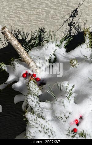 Weihnachtsdekorationen und Piniennadeln und rote Beeren bedeckt Schnee im Dezember Stockfoto