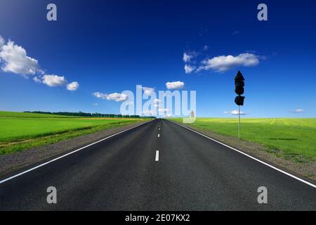 Neue Asphaltstraße mit weißen Fahrbahnmarkierungen. Das Straßenschild ist mit schwarzer Folie bedeckt, und das zweite ist gelb mit Geschwindigkeitsbegrenzung und Warnung. Auf den s Stockfoto