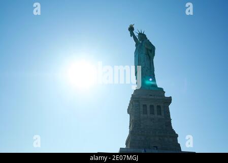 Silhouette der Freiheitsstatue, New York City, auf Liberty Island, New York, NYC. Blick von unten, mit der Sonne hinter der Statue, eine Silhouette. Stockfoto