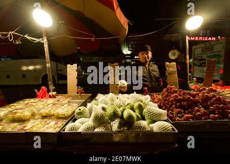 Ein Straßenhändler in Chinatown, New York, der Guava-Früchte und andere Früchte verkauft. Ein Mann, der Obst auf einem Markt in New York in China Town verkauft. Bowery. Stockfoto