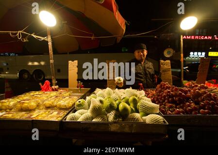 Ein Straßenhändler in Chinatown, New York, der Guava-Früchte und andere Früchte verkauft. Ein Mann, der Obst auf einem Markt in New York in China Town verkauft. Bowery. Stockfoto