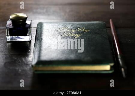 Geschlossenes Tagebuch mit Dib-Stift und Tintenfass auf dem Desktop Stockfoto