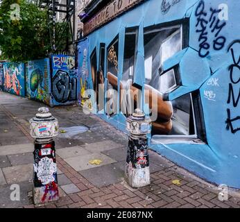 Fußweg von der Brick Lane zur nordöstlichen Ecke des Alien Gardens Parks in Shoreditch, Tower Hamlets, East London. Graditti deckt Wände und Poller ab. Stockfoto