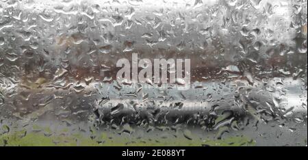 Mehrförmige Regentropfen auf Fensterglas mit Details. Stockfoto