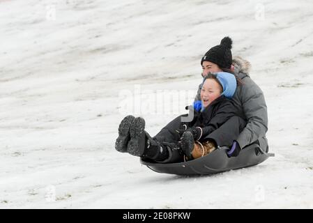 St. Charles, Illinois, USA. Dezember 2020. MISTY FEIZA und ihr Sohn BRANDON FEIZA, 8 aus South Elgin, IL, sled am Mittwoch, 30. Dezember 2020 den Hügel im Langum Park in St. Charles, IL hinunter. Die Region Chicago erhielt den ersten signifikanten Schneefall der Wintersaison 2020-2021. Kredit: Mark Black/ZUMA Wire/Alamy Live Nachrichten Stockfoto