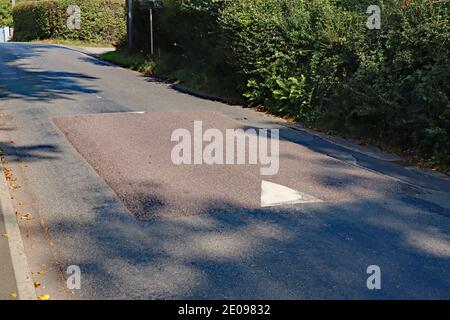 Ein Geschwindigkeitsüberschwauch in einem Dorf in Devon, das so konzipiert ist, dass es langsam wird Verkehr nähert sich der Dorfschule Stockfoto