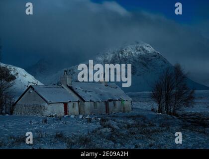 Glencoe, Schottland, Großbritannien. Dezember 2020. Im Bild: Hochlandhütte in Glencoe mit dem berühmten dreieckigen Berg Buachaille Etive Mòr im Hintergrund, dessen Gipfel in Wolken und eisigen Nebel gehüllt ist. Gelbe Schneewarnung an Ort und Stelle, da mehr Schnee mit frostigen Temperaturen über Nacht erwartet wird. Quelle: Colin Fisher/Alamy Live News Stockfoto