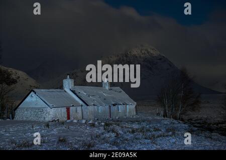 Glencoe, Schottland, Großbritannien. Dezember 2020. Im Bild: Hochlandhütte in Glencoe mit dem berühmten dreieckigen Berg Buachaille Etive Mòr im Hintergrund, dessen Gipfel in Wolken und eisigen Nebel gehüllt ist. Gelbe Schneewarnung an Ort und Stelle, da mehr Schnee mit frostigen Temperaturen über Nacht erwartet wird. Quelle: Colin Fisher/Alamy Live News Stockfoto