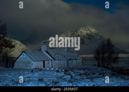 Glencoe, Schottland, Großbritannien. Dezember 2020. Im Bild: Hochlandhütte in Glencoe mit dem berühmten dreieckigen Berg Buachaille Etive Mòr im Hintergrund, dessen Gipfel in Wolken und eisigen Nebel gehüllt ist. Gelbe Schneewarnung an Ort und Stelle, da mehr Schnee mit frostigen Temperaturen über Nacht erwartet wird. Quelle: Colin Fisher/Alamy Live News Stockfoto