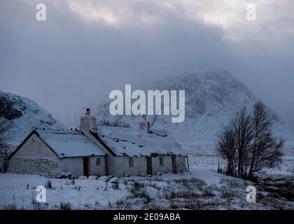 Glencoe, Schottland, Großbritannien. Dezember 2020. Im Bild: Hochlandhütte in Glencoe mit dem berühmten dreieckigen Berg Buachaille Etive Mòr im Hintergrund, dessen Gipfel in Wolken und eisigen Nebel gehüllt ist. Gelbe Schneewarnung an Ort und Stelle, da mehr Schnee mit frostigen Temperaturen über Nacht erwartet wird. Quelle: Colin Fisher/Alamy Live News Stockfoto