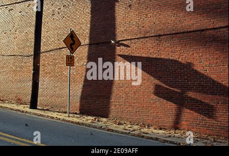 Verkehrszeichen und sein Schatten auf einer Ziegelmauer. Stockfoto