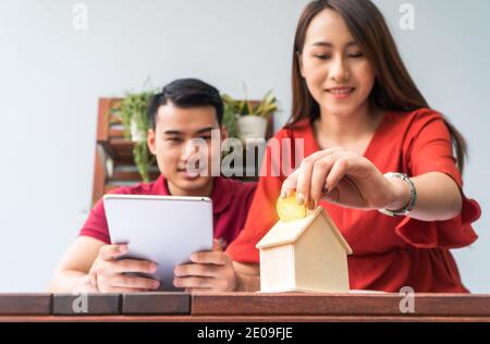 Selektiver Fokus der goldenen Münze. Asiatische Paare glücklich lächelnd, weil es von Investitionen rentabel ist und Einsparungen für den Kauf einer Wohnung und accommodat Stockfoto
