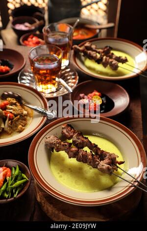 Sate Klatak, der javanische Lammspieß auf dem Fahrrad, serviert mit Gelber Curry-Suppe und Konditionierung von Schalotte, Tomate, Chili-Sauce, Sojasoße Stockfoto