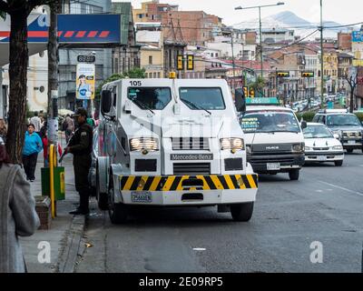 Ein Mercedes-Benz gepanzerter Sicherheitswagen überweist Bargeld vor eine Bank in La Paz, Bolivien, während ein Wachmann mit einer Schrotflinte dazusteht Stockfoto