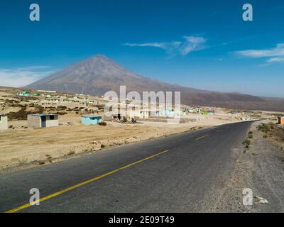 Eine Straße am Stadtrand von Arequipa, Peru. Kleine Betonhütten sind durch das Gebiet verstreut, während der Vulkan Misti dahinter zu sehen ist Stockfoto