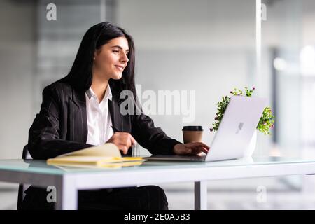 Nahaufnahme fokussierte junge Geschäftsfrau, die mit Dokumenten im Büro arbeitet, am Arbeitstisch mit Laptop sitzt, seriöse Angestellte, die den Finanzbericht überprüft, Stockfoto