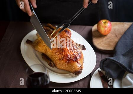 Frau schneidet knusprig geröstete Ente auf einem weißen Teller Stockfoto