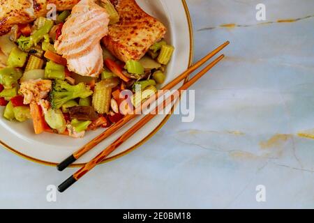 Frisch gekochter Lachs auf Teller mit Salat und Zitrone auf weißem Holzhintergrund. Stockfoto