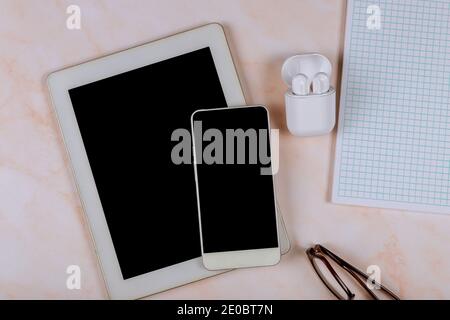 Draufsicht Büroschreibtisch Gadgets mit kabellosen Ladekopfhörer Digital Tablet und Smartphone, Brille, Stift, Notebooks im Marmortisch Hintergrund Stockfoto