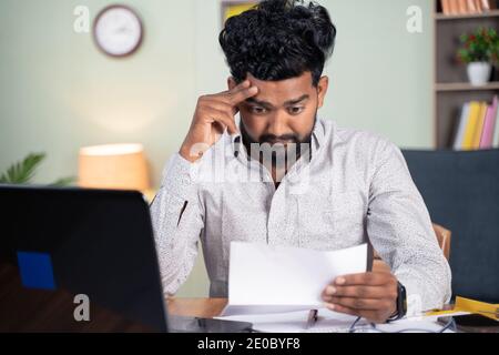 Der junge Mann wurde enttäuscht, nachdem er Briefpapier gelesen hatte - Konzept der schlechten Nachrichten, Kündigung des Arbeitsplatzes, Geschäftsschluss oder Räumungserklärung. Stockfoto