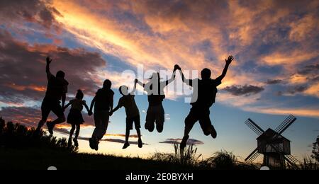 Hüpfen einer Familie den Sonnenuntergang Hand in Hand Stockfoto
