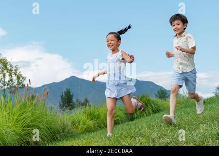 Glückliche Kinder laufen auf dem Gras Stockfoto