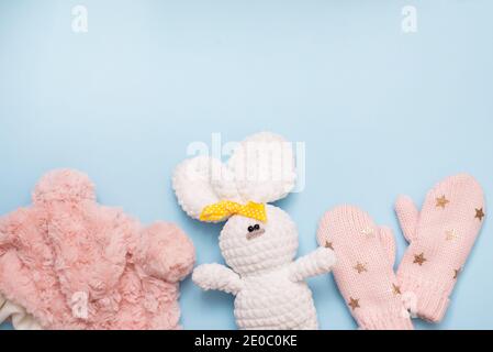 Baby Winter Kleidung rosa Hut und Fäustlinge auf blauem Hintergrund mit weißem Spielzeug Kaninchen, kopieren Raum. weihnachtsurlaub Stockfoto