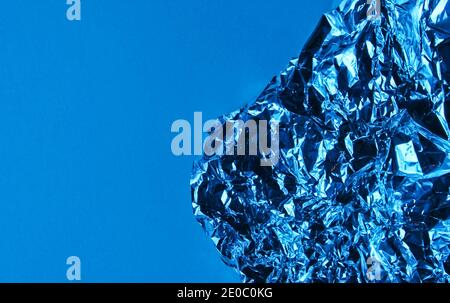 Zerknitterte Folie auf blauem Hintergrund mit Neonlicht Stockfoto