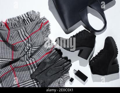 Herbstgarderobe. Damenartikel, Schuhe und Accessoires auf weißem Hintergrund. Wildlederstiefel, Tasche, Lederhandschuhe, Flasche Parfüm, Schal. Flach liegend Stockfoto
