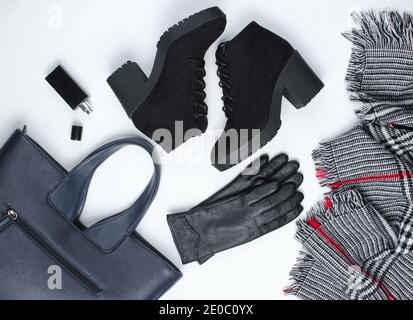Herbstgarderobe. Damenartikel, Stiefel und Accessoires auf weißem Hintergrund. Wildlederschuhe, Tasche, Lederhandschuhe, Flasche Parfüm, Schal. Flach liegend Stockfoto
