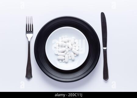 Platte von Pillen mit Messer und Gabel. Isoliert.Draufsicht, pharmakologisches Konzept. Weiße Pillen Stockfoto