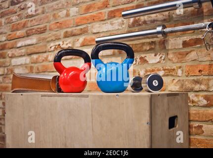 Funktionales Trainingskonzept. Kettlebell, Hantelständer auf Holzkiste gegen den Backstein Wand Hintergrund. Trainingsgeräte Stockfoto