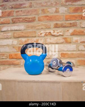 Funktionales Trainingskonzept. Kettlebell, Hantelständer auf Holzkiste gegen den Backstein Wand Hintergrund.Funktionelles Trainingskonzept.Gratis Gewichtstraini Stockfoto