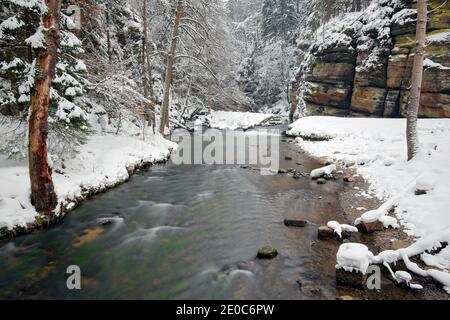 Winterlandschaft mit weißem Fluss, großer Felsen im Hintergrund. Kamenice Fluss, im tschechischen Nationalpark, Ceske Svycarsko, Böhmische Schweiz Park, CZE Stockfoto