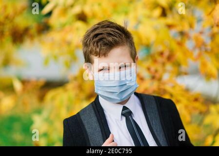 Schuljunge geht aus der Schule tragen Schutzmaske in der Stadt Stockfoto