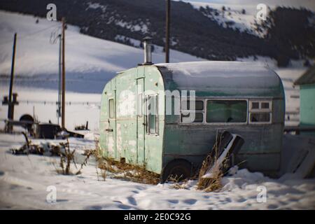 Ein alter, verwitterter Reiseanhänger der Schnee, auf einer Farm in Porter's Corner, südwestlich von Philipsburg, in Granite County, Montana, am Fuße des Stockfoto