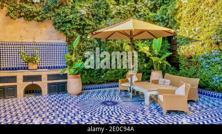 Fez, Marokko - 30. Oktober 2015. Ein Beispiel für den marokkanischen Innenhof mit blauen und weißen Fliesen, Gartenmöbeln und Gartenpflanzen. Stockfoto