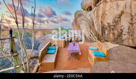 Rural Namibia - 21. August 2016. Eine einzigartige Küche und Sitzecke im Freien ist auf einer Terrasse zwischen großen alten Felsbrocken in einer Wüstenlandschaft gebaut. Stockfoto