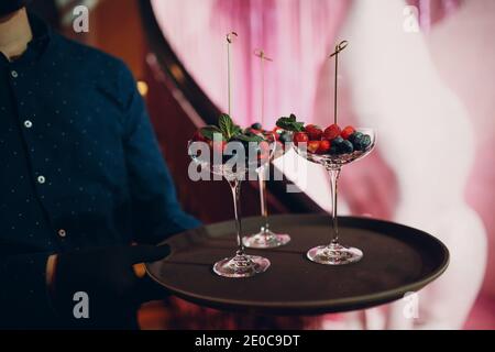 Kellner serviert ein Gericht in einem Restaurant mit Glas Beeren. Stockfoto