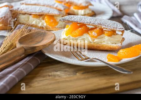 Süßer Blätterteig mit Schlagsahne und Mandarinenfüllung Eine Platte mit Gabel Stockfoto