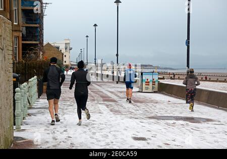 Portobello, Edinburgh, Schottland, Großbritannien. 31 Dezember 2020. UK Wetter: Nach buntem Sonnenaufgang hatte Porty einen frühen Schneeschauer, am Meer. Im Bild: Die Leute trainieren am letzten Tag des 2020. Quelle: Arch White/Alamy Live News. Stockfoto