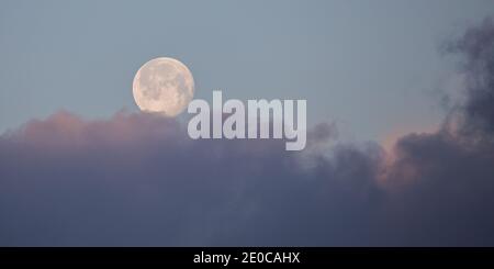 Aberystwyth, Ceredigion, Wales, Großbritannien. 31. Dezember 2020 UK Wetter: Ein kalter Morgen in Aberystwyth, als der letzte Vollmond 2020 zu untergehen beginnt, mit dem Sonnenaufgang, der Bereiche der tief liegenden Wolke über dem Pendinas-Denkmal aufhellt. Während die Temperatur heute Morgen an der Westküste auf minus 1 Grad sinkt. © Ian Jones/Alamy Live News Stockfoto