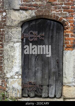 Große verwitterte Holztür mit großen rostigen Scharnieren Stockfoto