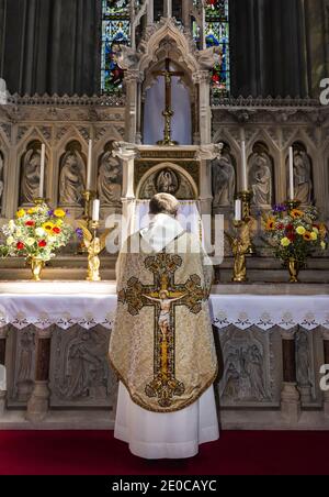 Priester steht am Altar in der St. Mary's und St. John's Church in Wolverhampton, West Midlands, England, Großbritannien Stockfoto