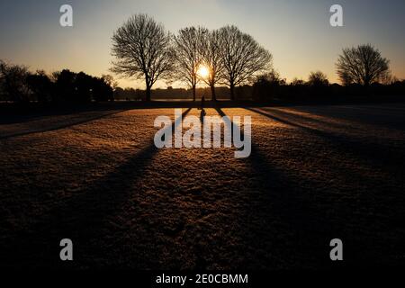 Bingham, Nottinghamshire, Großbritannien. Dezember 2020. Eine Frau ist im Schatten, als sie ihren Hund an einem frostigen Morgen in Bingham, Nottinghamshire, spaziert. Neil Squires/Alamy Live News Stockfoto