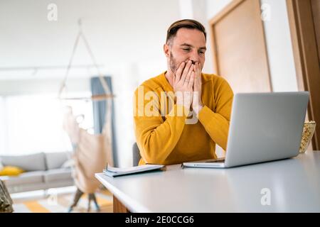 Verärgert junger Mann zählt Familie Haushalt auf Laptop Stockfoto