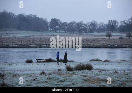 Am frühen Morgen standen Spaziergänger an einem Teich in einem frostbedeckten Richmond Park im Südwesten Londons, während eines kalten Starts in den Tag in der Hauptstadt, nachdem die Nachttemperaturen unter den Gefrierpunkt gefallen waren. Stockfoto