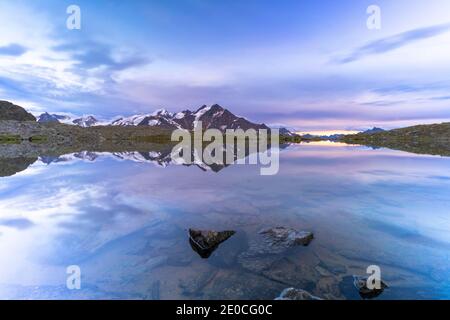 Sonnenuntergang über dem klaren Wasser des Manzina Sees mit Tresero Gipfel im Hintergrund, Valfurva, Valtellina, Lombardei, Italien, Europa Stockfoto