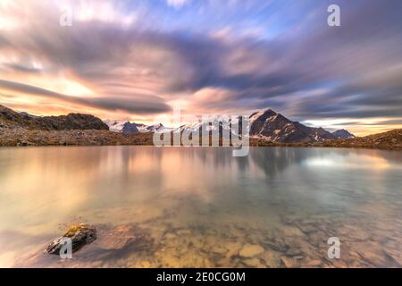 Dramatischer Himmel bei Sonnenaufgang über Tresero Gipfel spiegelt sich in See Manzina, Valfurva, Valtellina, Sondrio Provinz, Lombardei, Italien, Europa Stockfoto